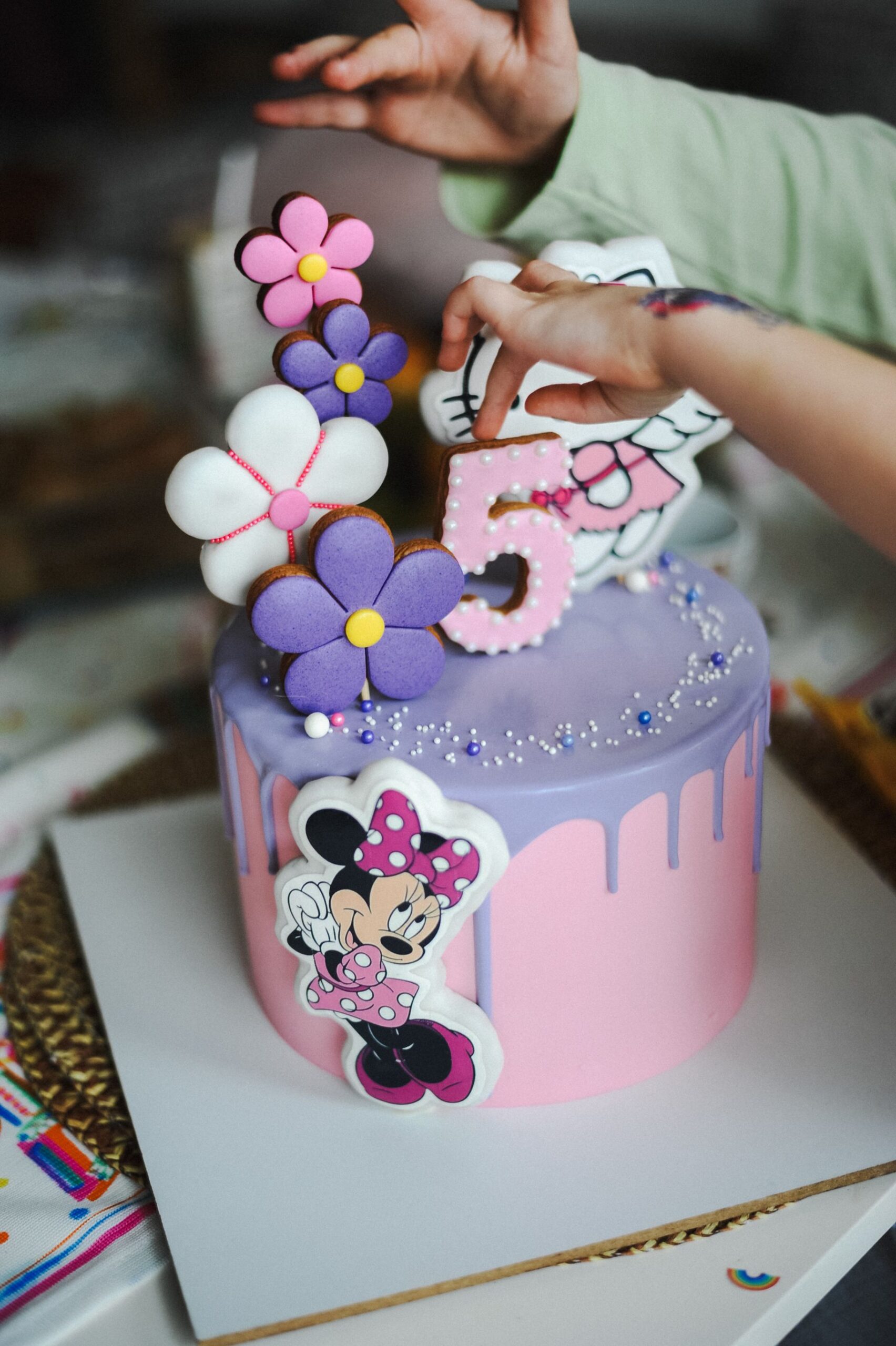 A vibrant cartoon-themed birthday cake decorated with figures and flowers.